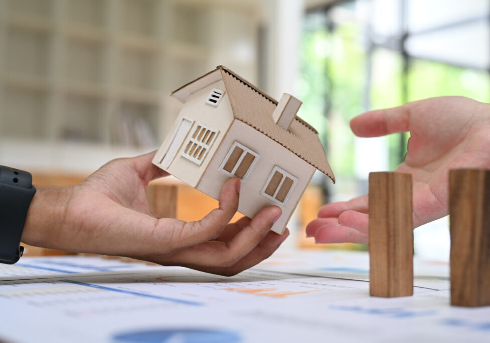 Close up view two investor or young couple holding small house model. Real estate, mortgage loan and home insurance concept.